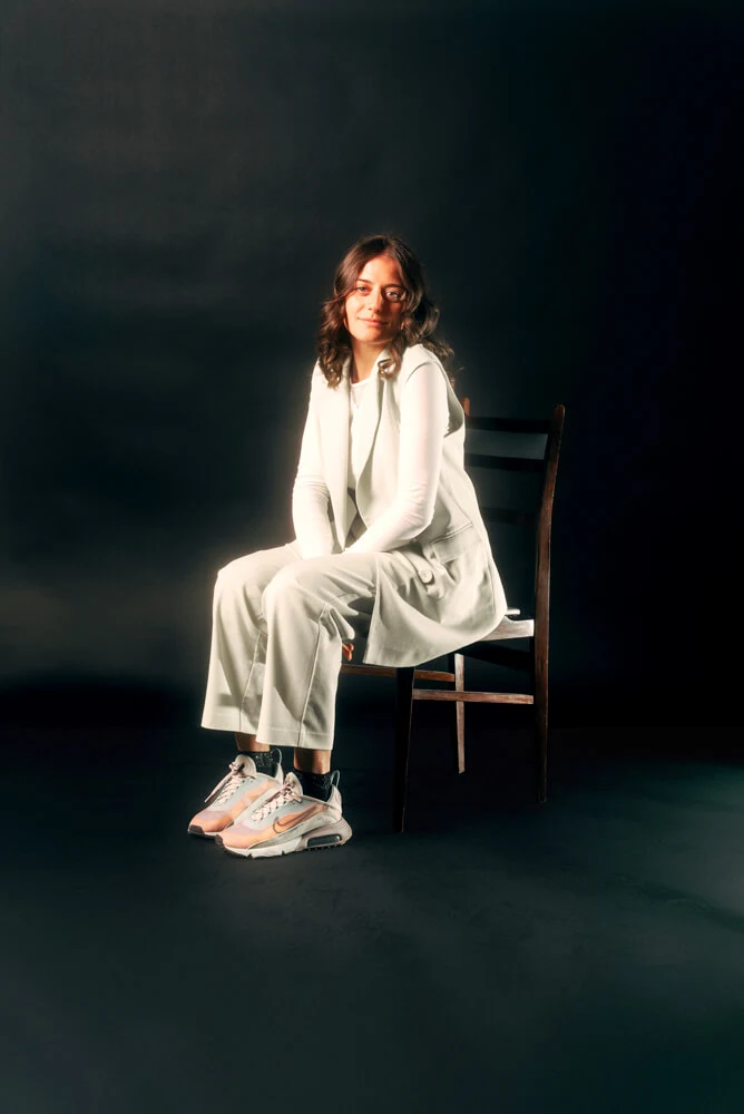 One of our designer seated on a chair against a black background