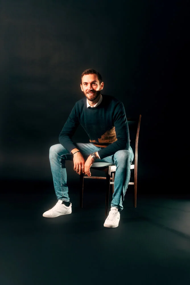One of our developers seated on a chair against a black background